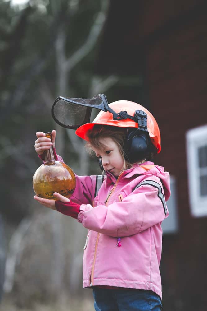 A girl wearing safety gear doing experiments at the backyard.