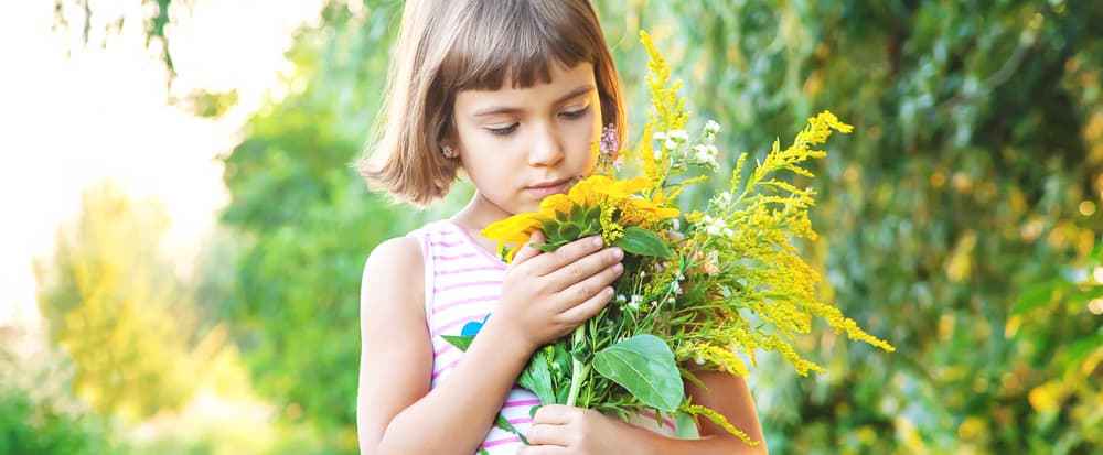 A close look at a girl holding a bouquet of wildflowers.
