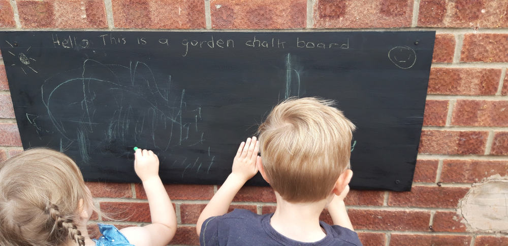 Kids playing a chalkboard message center.