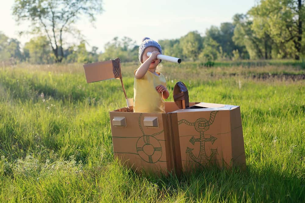 A kid playing on a makeshift carton boat.