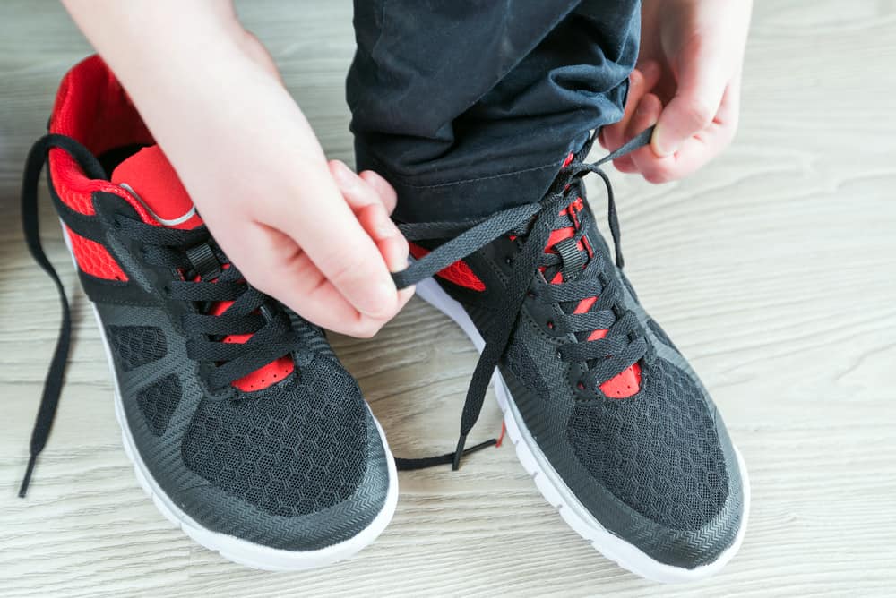 A close look at a boy lacing his sports shoes.