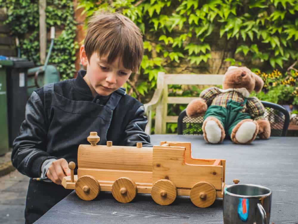 A boy playing with a recycled wooden toy truck.