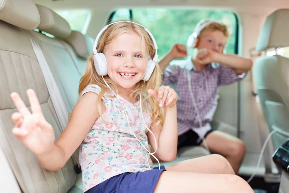 children listening to music with their headphones in the car.