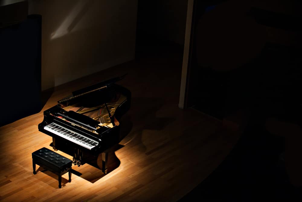 11 Popular Types of Pianos 9 A view of the concert grand piano on a dark stage.
