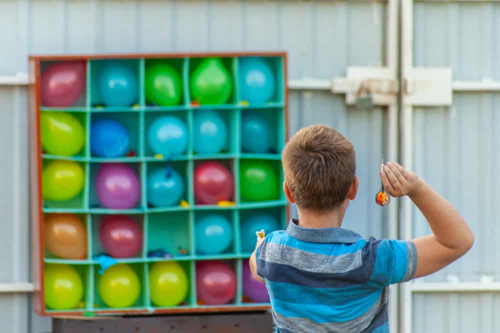 A boy playing balloon darts.
