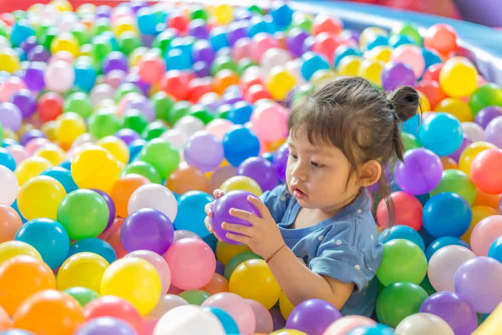 A girl playing in the ball pit.