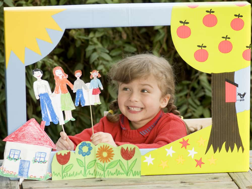 Girl playing with a puppet theater.
