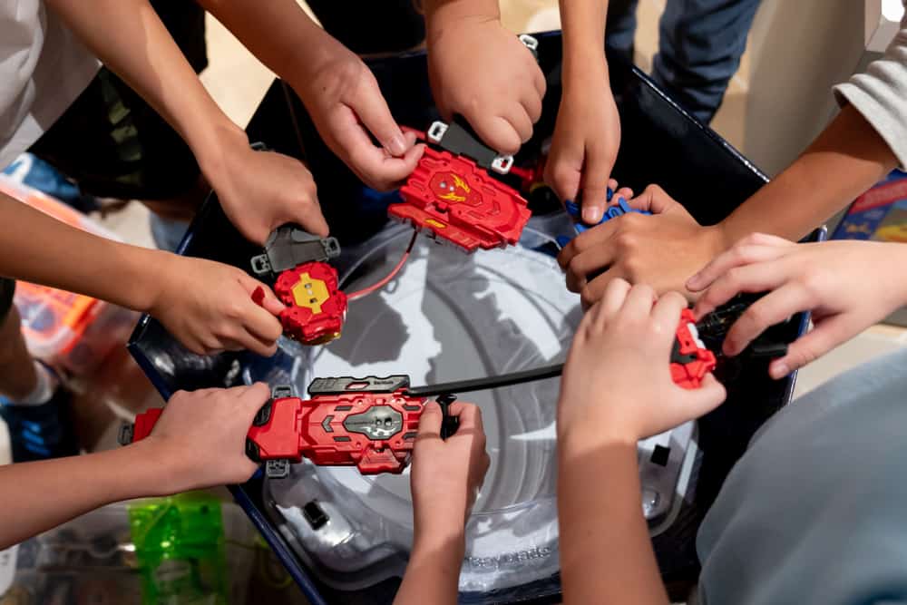 Kids holding their beyblade launcher over a beyblade stadium. Toys similar to beyblade.
