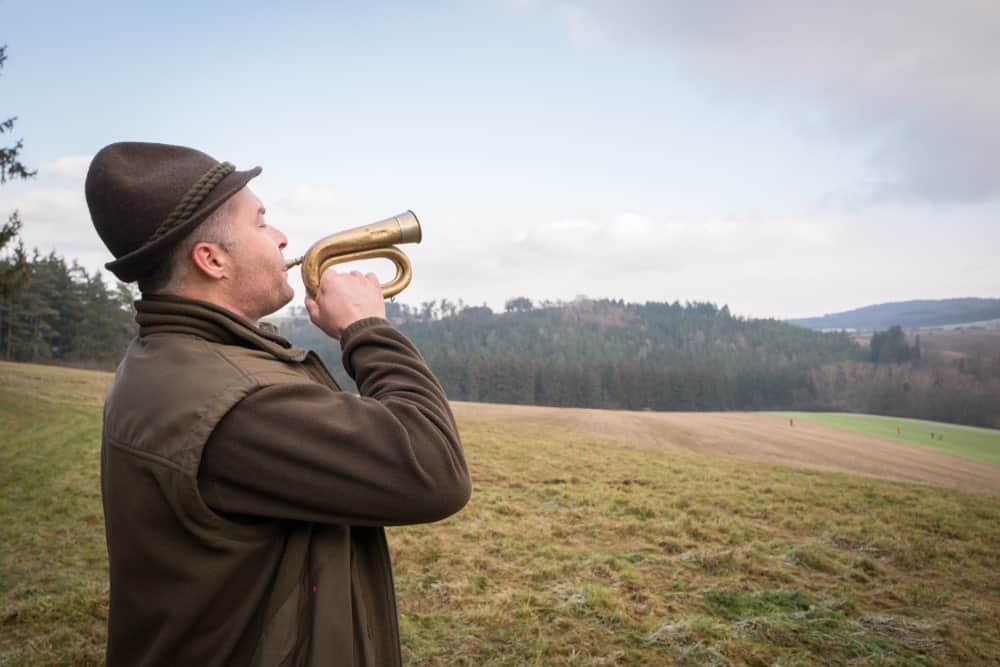9 Popular Types of Trumpets Explained 5 Old man using a bugle at a farm.