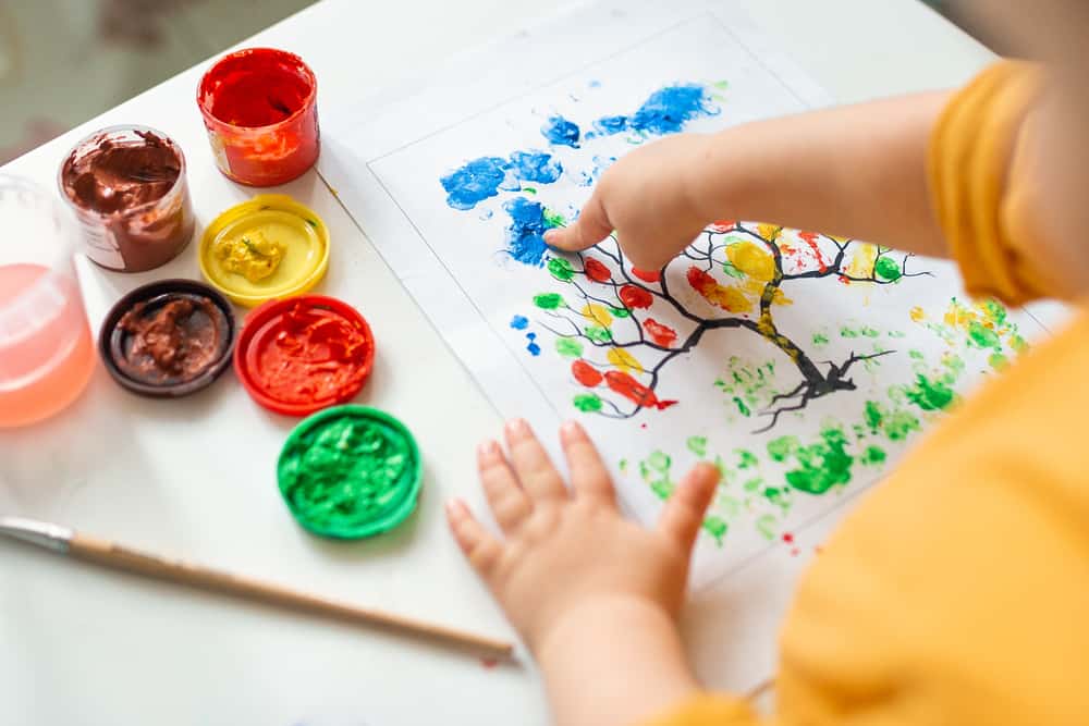 22 Best Drawing Toys for Kids Who Like to Draw 11 Little girl painting a tree using her fingers.
