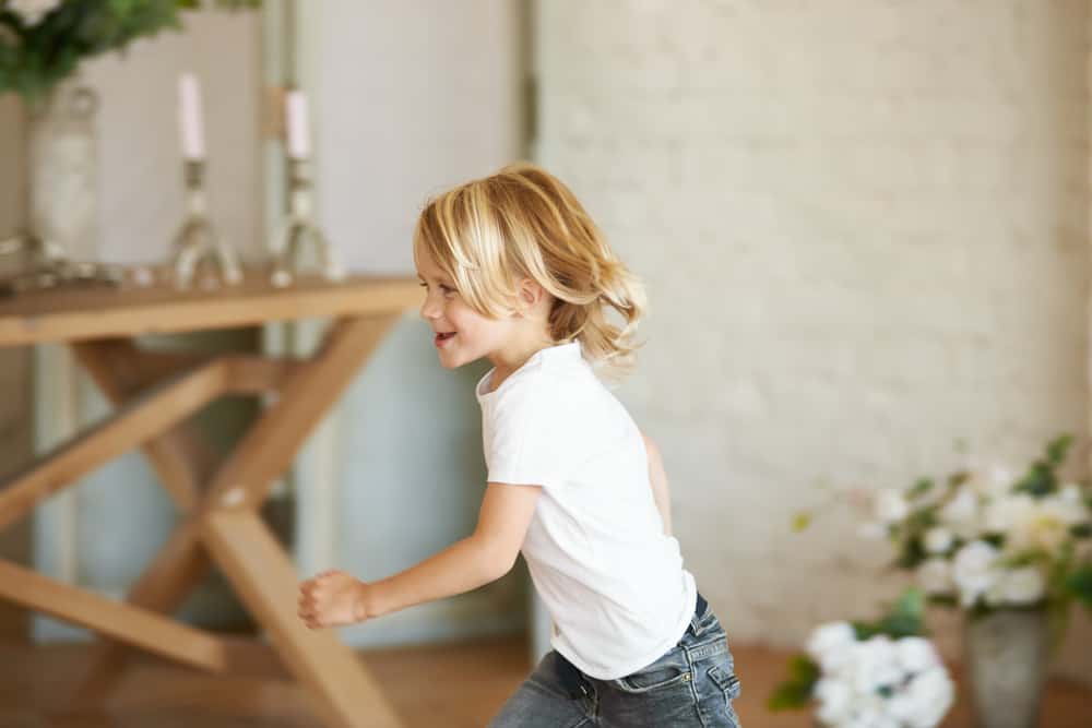 Little boy running around the room, playing tag.