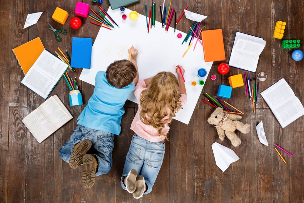 Little boy and girl lying and drawing on a white pad. Drawing toys for kids.