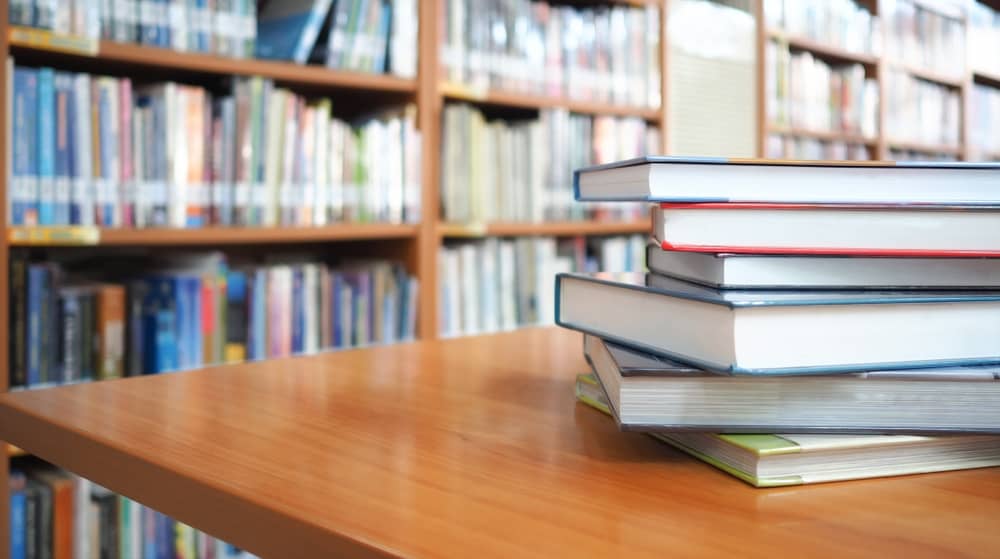 A pile of books over a wooden table inside the library.
