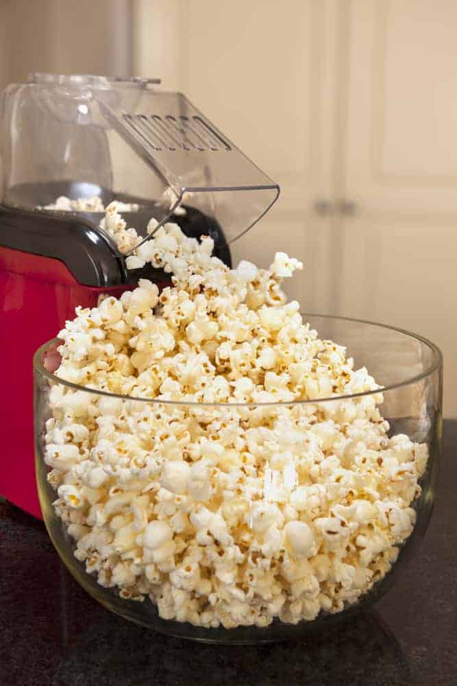 Popcorn maker filling up a large bowl with popcorn.