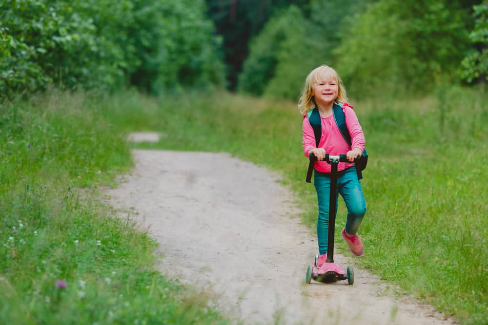 Kid riding a scooter in the field.