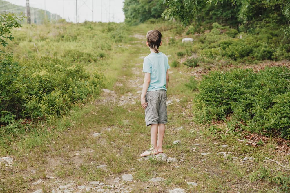 Boy standing on the country road and looking into the distance.