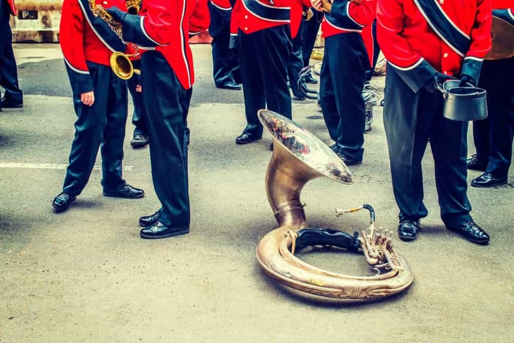 Sousaphone resting on the concrete ground as the marching band stands idly.