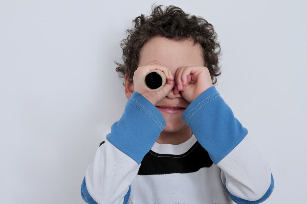 Boy looking through toilet paper roll.