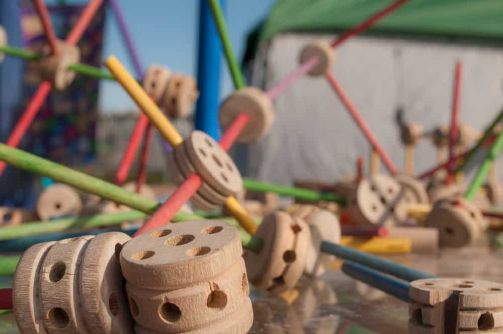 This is a close look at a bunch of wooden vintage tinker toys on the ground.