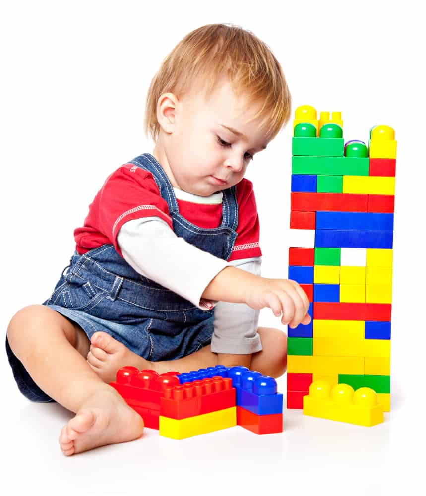 A toddler playing with big colorful building blocks.