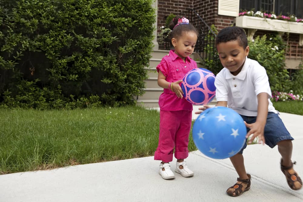 This is a close look at two kids playing with colorful patterned balls.