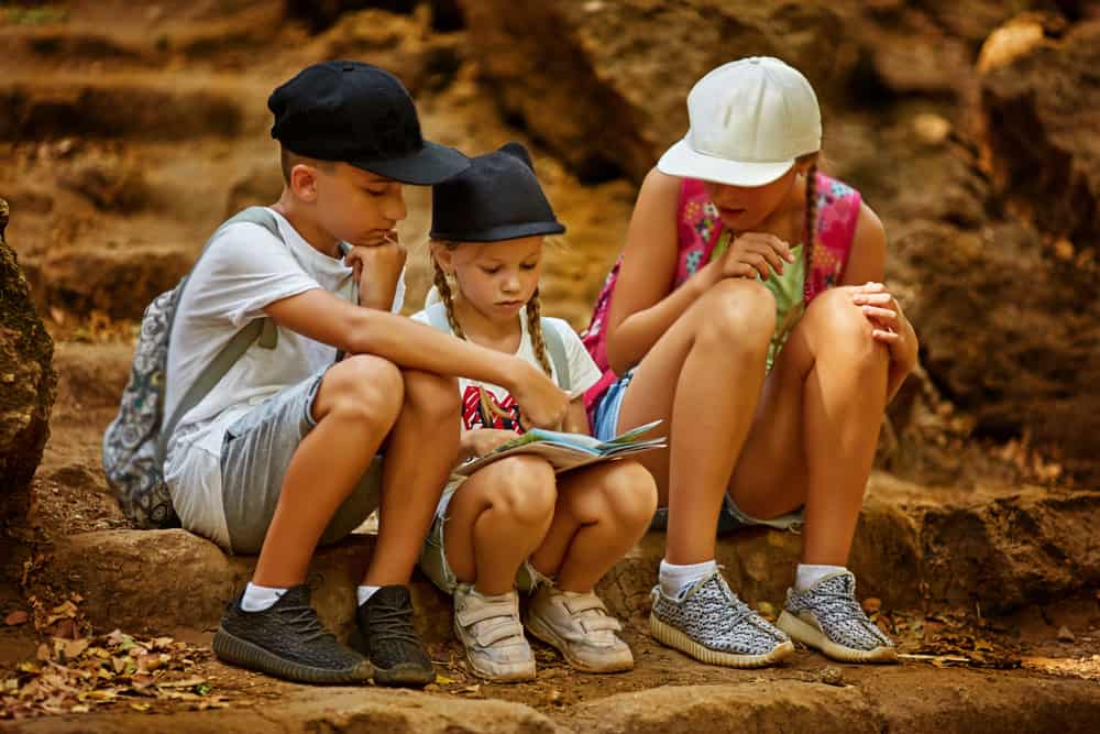 Kids navigating on map during treasure hunt game.