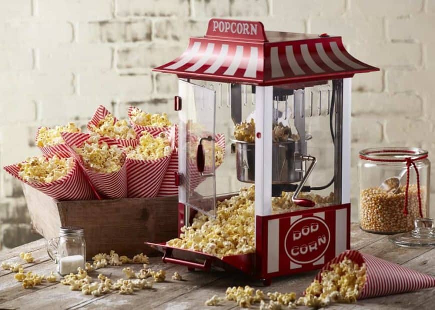 Cute popcorn maker surrounded by cones of popcorn.
