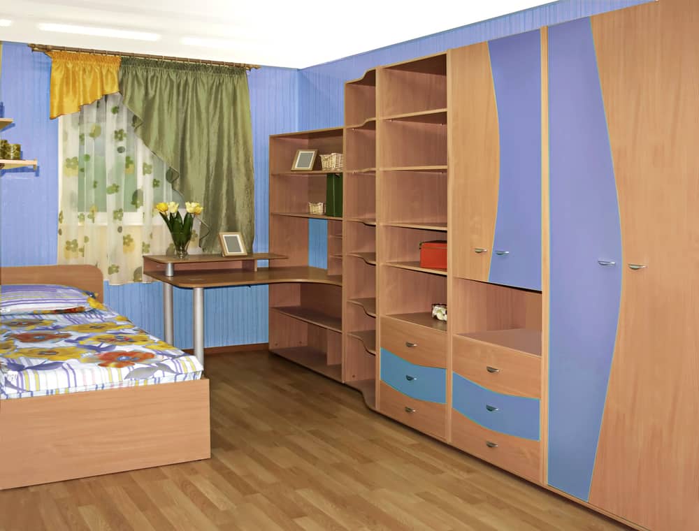 Kid's bedroom with a wardrobe desk and a cozy wooden bed.