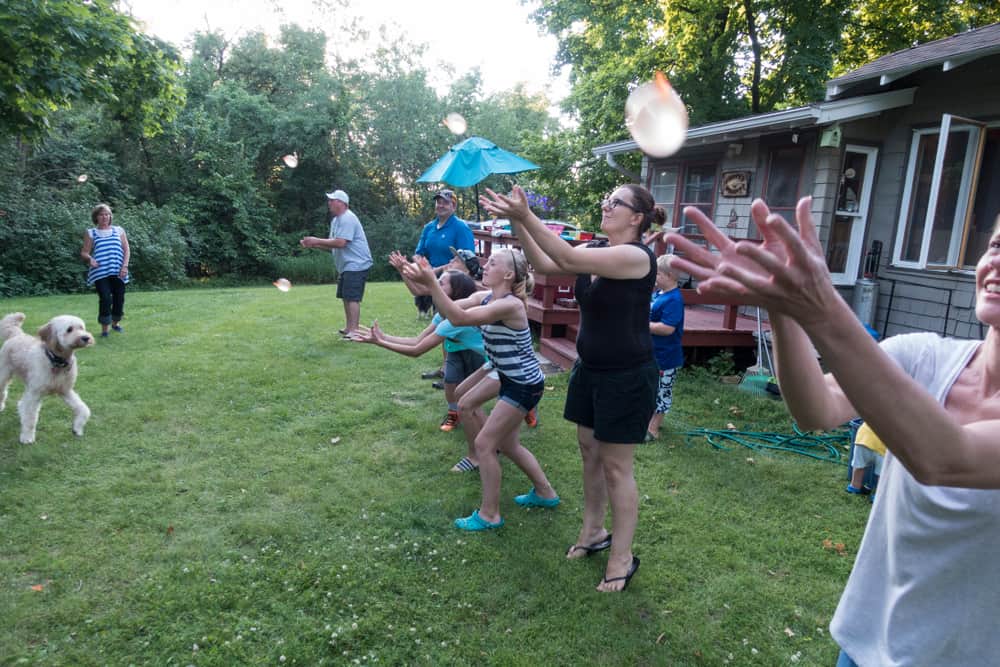 People playing water balloon toss in the yard.
