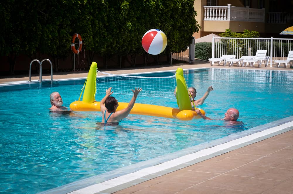 Old people playing volleyball at the pool.
