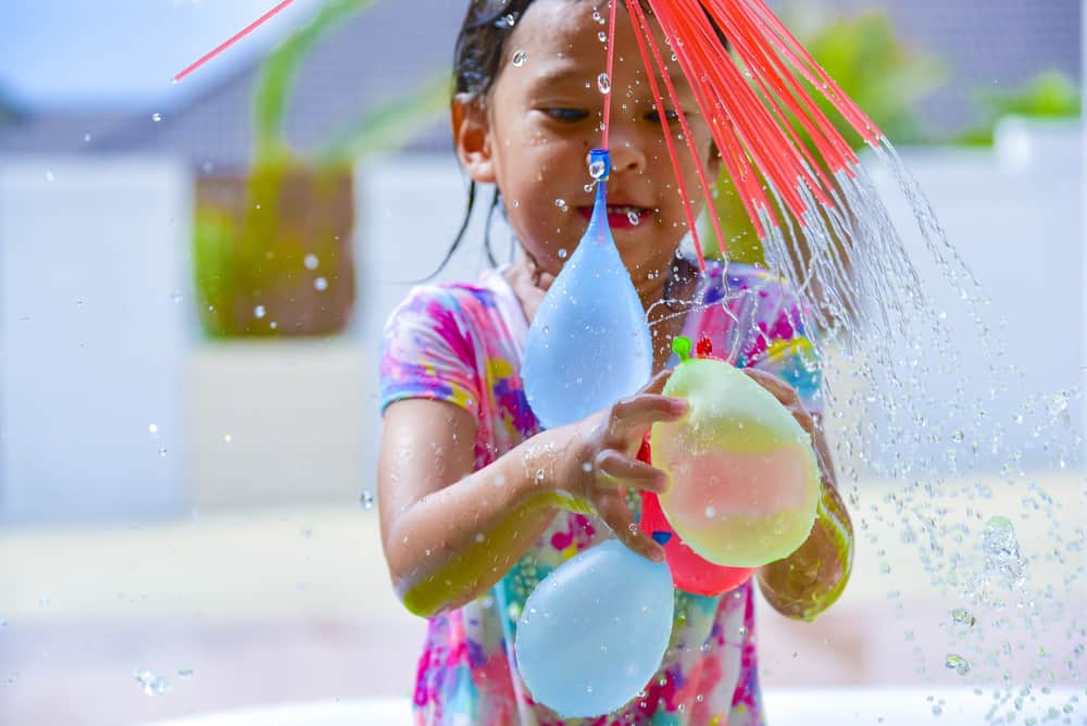 A little girl playing with water balloons.