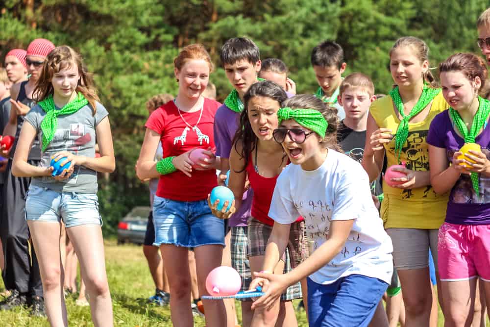 Kids and teens playing water balloon fight.