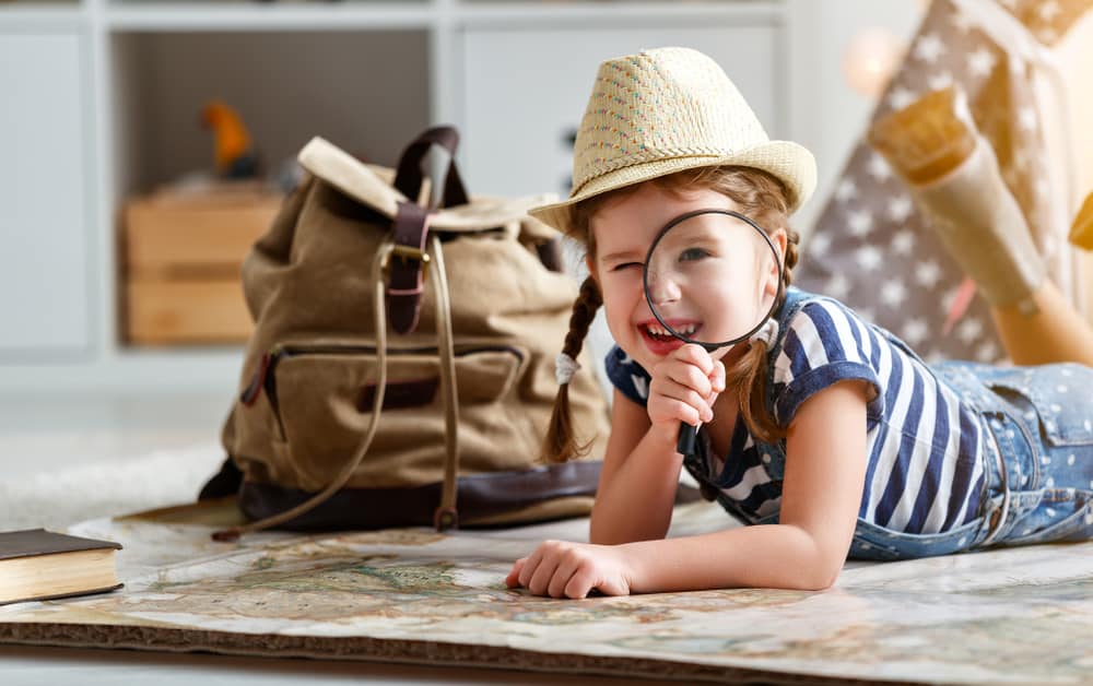 Girl plays tourist with a agnifying glass and a map.