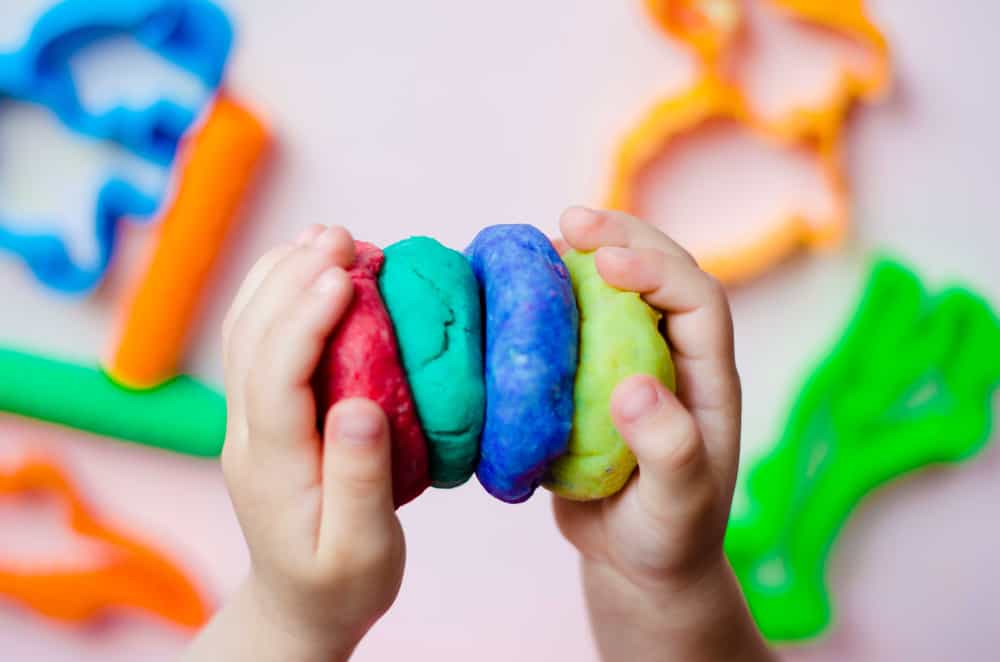 This is a close look at a kid playing with colorful playdough.