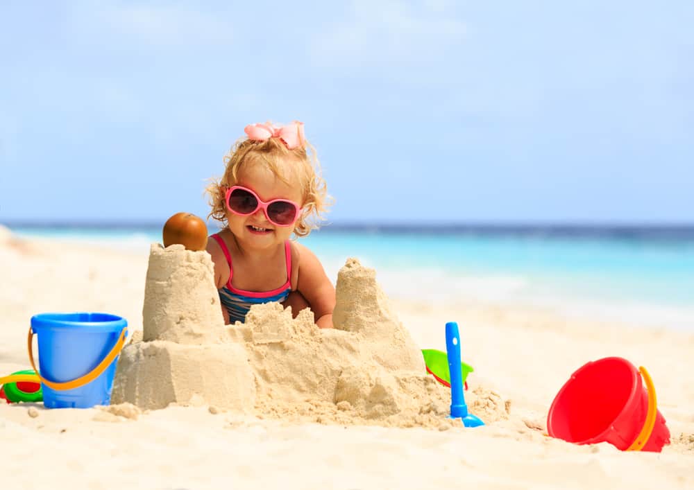 A girl playing with sand at the beach.