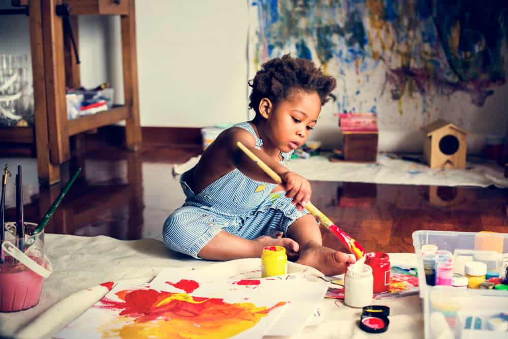 200 Best Indoor Activities for Kids 15 A little boy on a work table making a painting.
