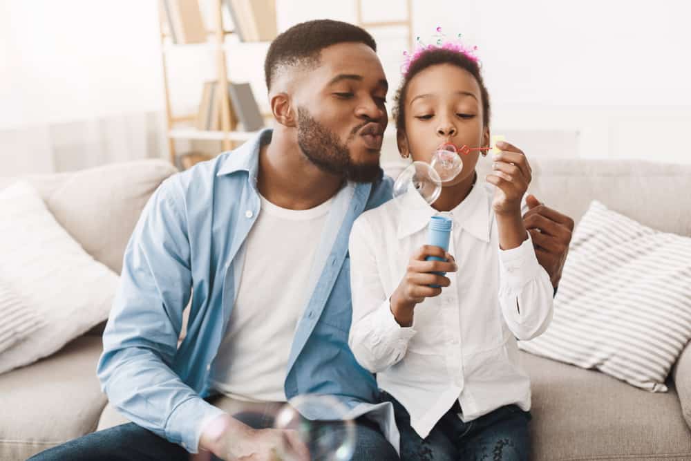200 Best Indoor Activities for Kids 18 A father and daughter playing with bubbles in living room.