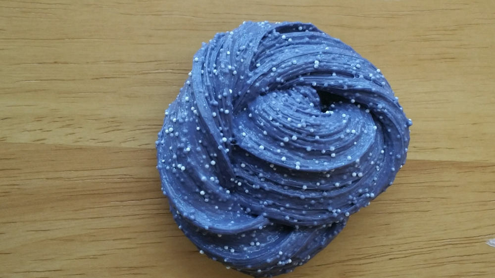 This is a dark blue microfloam slime on a wooden table.