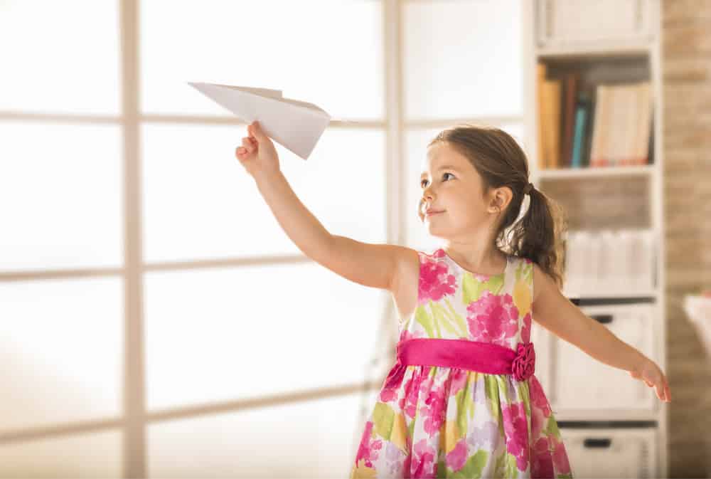 200 Best Indoor Activities for Kids 4 This is a close look at a kid playing with a paper airplane.