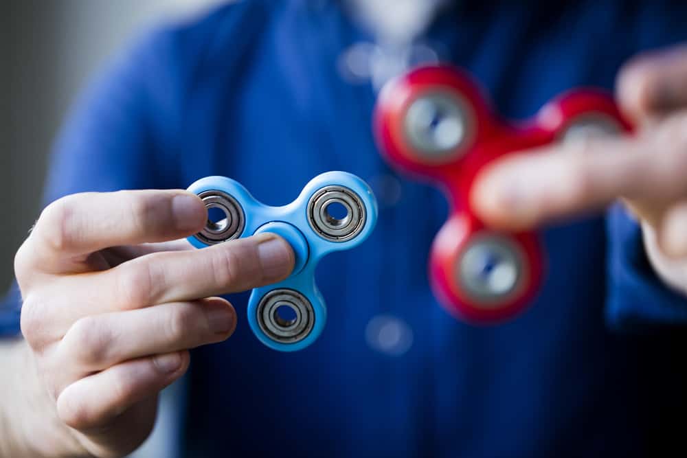 A close look at a man playing with a couple of fidget spinners.