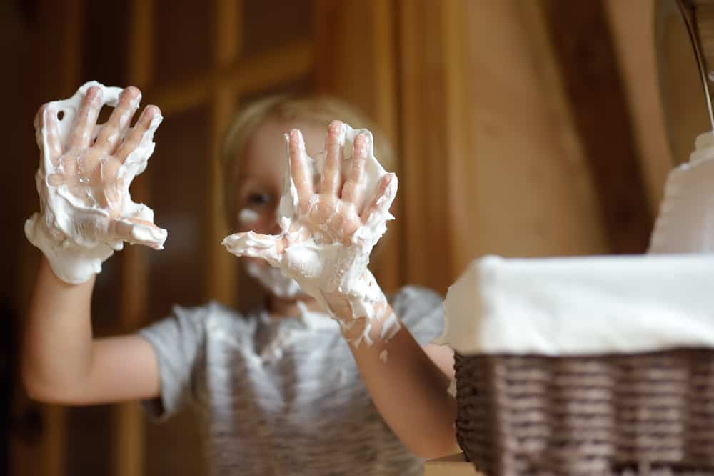 A close look at a boy playing with shaving cream foam.