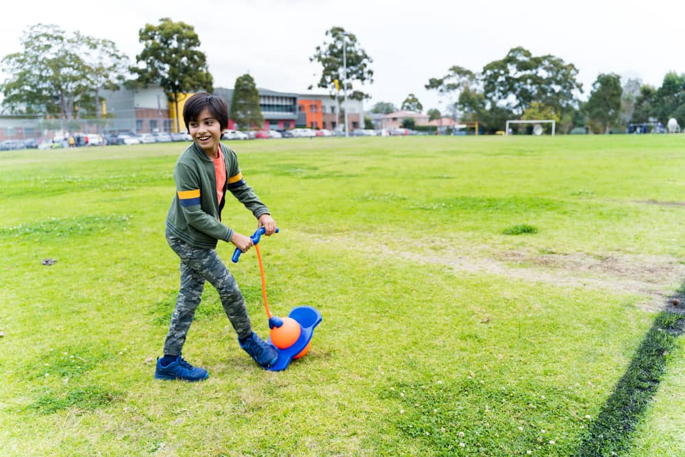 A kid playing with a pogo stick toy at the park.