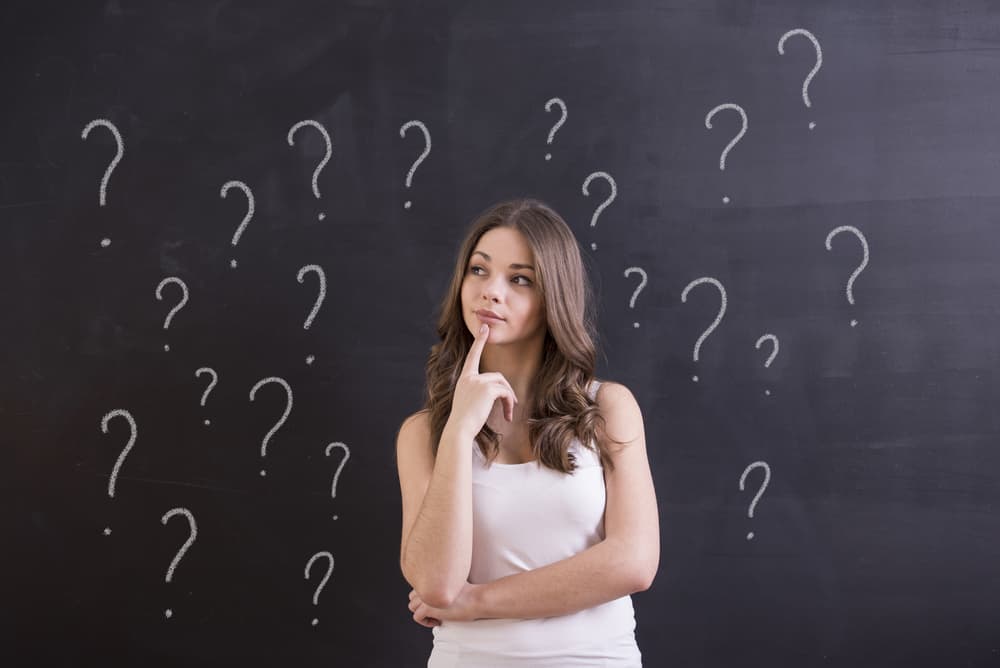 250 Best Would You Rather Questions for Teens 8 This is a close look at a teen girl with question marks written on the chalkboard behind her.