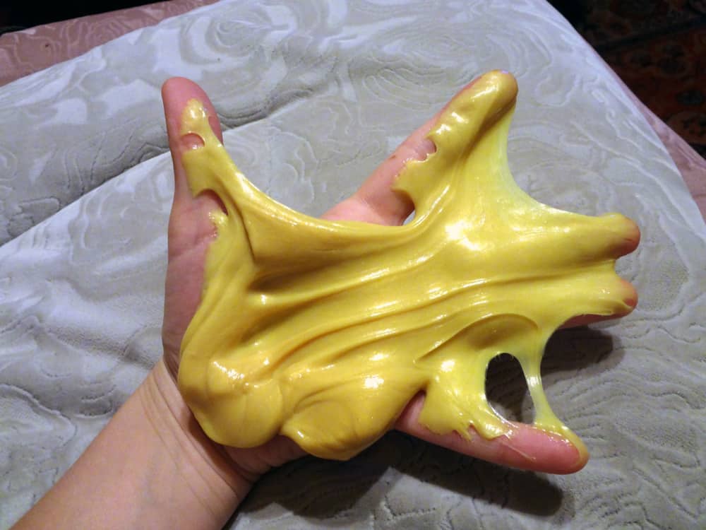 A yellow silly putty on a hand.