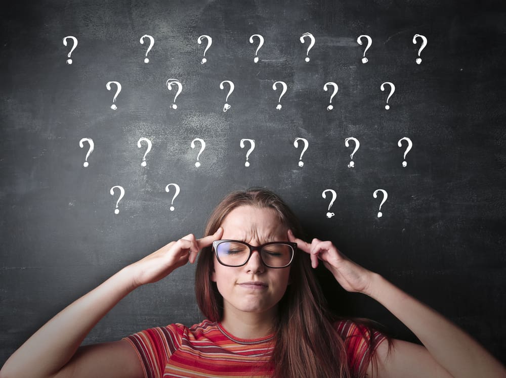 250 Best Would You Rather Questions for Teens 9 This is a girl concentrating hard with question marks written on the chalkboard behind her.