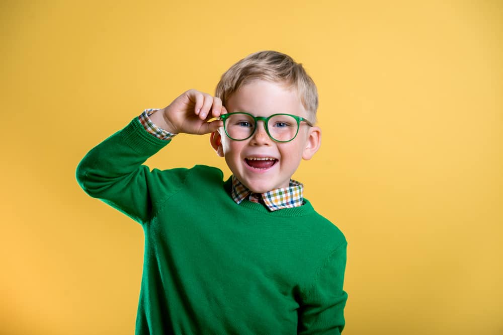 This is a three-year-old boy wearing a green sweater and a green pair of glasses.