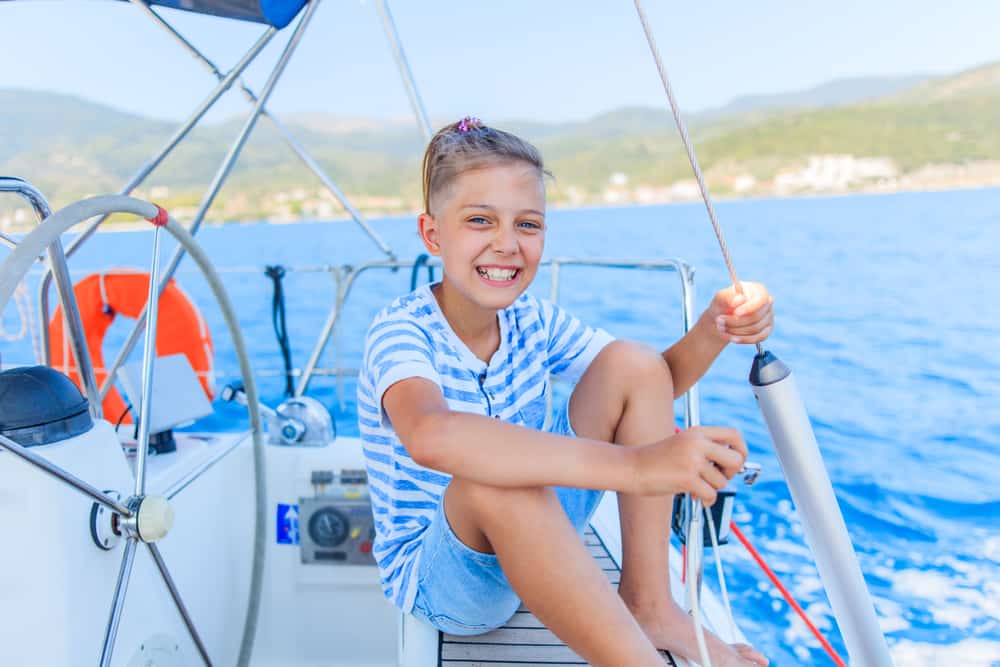 Boy sitting on a yacht while sailing on a summer cruise.
