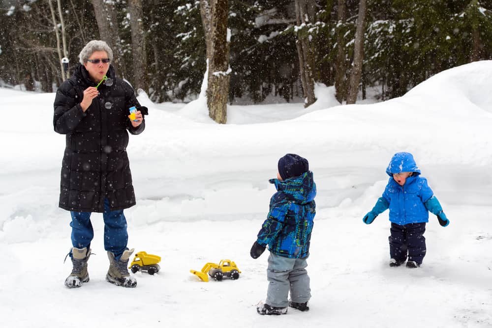50 Best Science Activities for Kids 4 Grandmother blows bubbles for two little boys outside the snow.