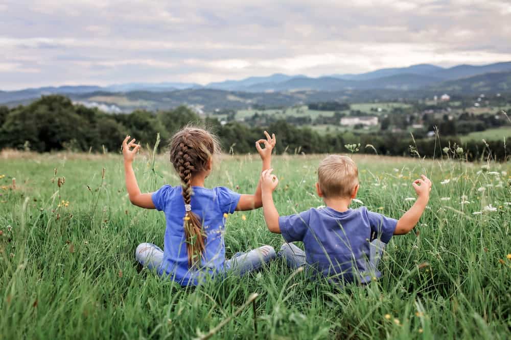 Little kids doing yoga on the top of the mountains.
