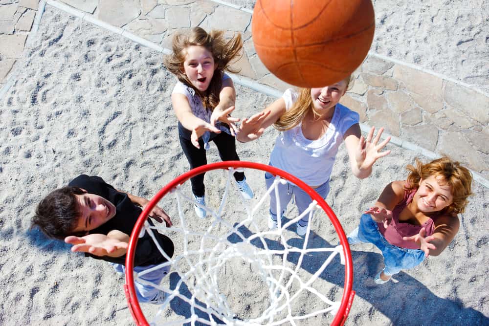 A group of teens playing basketball in the park.